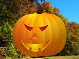 Halloween, giant carved pumpkin, on a footpath at the edge of a wood in autumn