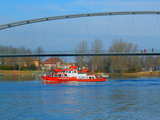 The ship of the Fire Brigade of Basel, Switzerland, passing under the footbridge on the Rhine, Passerelle des 3 Pays, Dreiländerbrücke, near the border triangle France-Germany-Switzerland, February 2009, HDR picture
