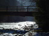 Contre-jour d'un petit pont, eau et glace éblouissantes, à la rivière Schwarzwasser, dans le Mittelland en Suisse