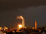 Réflection de rayons de soleil couchant et nuages sombres, les rayons du soleil couchant passent par une lucarne près de l'horizon, alors qu'il y a des nuages d'orage très sombres dans le sud, le bâtiment éblouissant est l'usine d'incinération des déchets de Bâle, Suisse, Juillet 2007